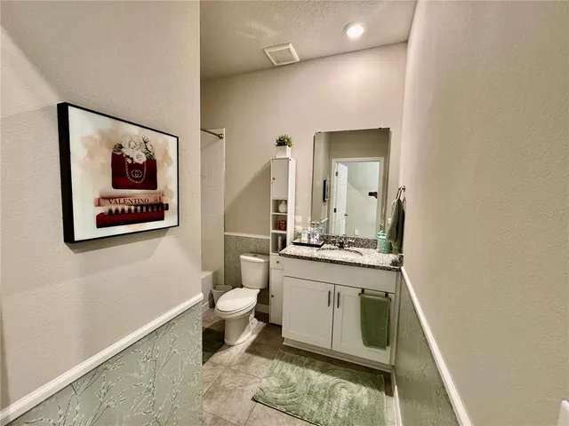 a bathroom with a granite countertop toilet sink and mirror