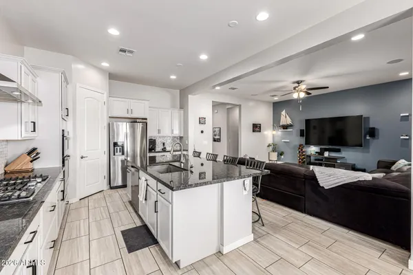 a kitchen with stainless steel appliances granite countertop a table chairs stove a refrigerator and cabinets