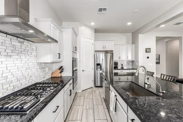 a kitchen with stainless steel appliances a stove a sink a refrigerator and a living room view