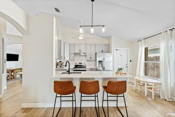 a kitchen with stainless steel appliances kitchen island granite countertop a dining table chairs and white cabinets