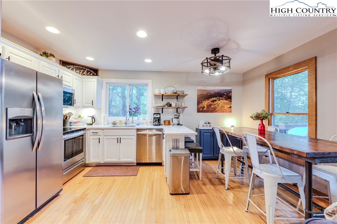 888 Benjamin Drive Boone, NC 28607 - Photo 7 of 38 a kitchen with stainless steel appliances granite countertop a refrigerator a sink dishwasher a dining table and chairs with wooden floor