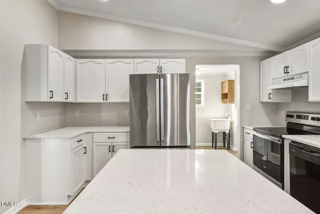 a kitchen with stainless steel appliances a stove top oven a refrigerator a sink and dishwasher with white cabinets