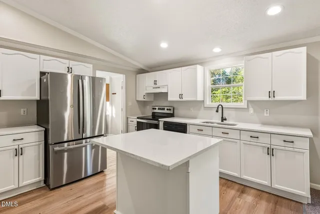 a kitchen with a refrigerator a sink cabinets and wooden floor