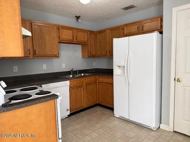 a kitchen with stainless steel appliances granite countertop a refrigerator a sink and white cabinets