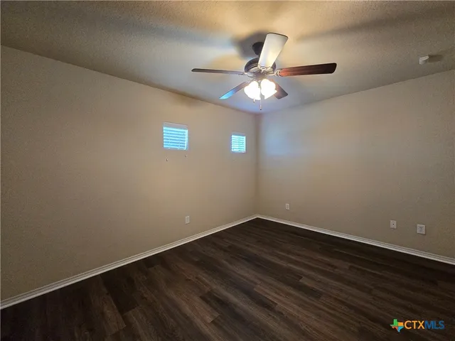 en empty room with wooden floor and ceiling fan