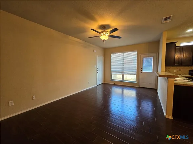 a view of an empty room with window and wooden floor