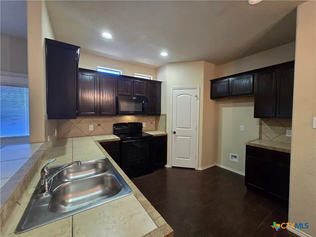 a kitchen with granite countertop stainless steel appliances a sink and a refrigerator