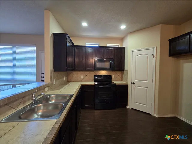 a kitchen with a sink and a stove top oven with wooden floor