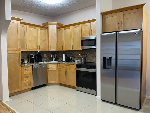 a kitchen with stainless steel appliances granite countertop a refrigerator a sink and a stove