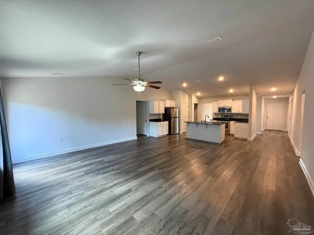 an empty room with wooden floor kitchen view and a view