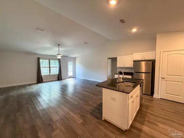 a kitchen with granite countertop a sink and refrigerator