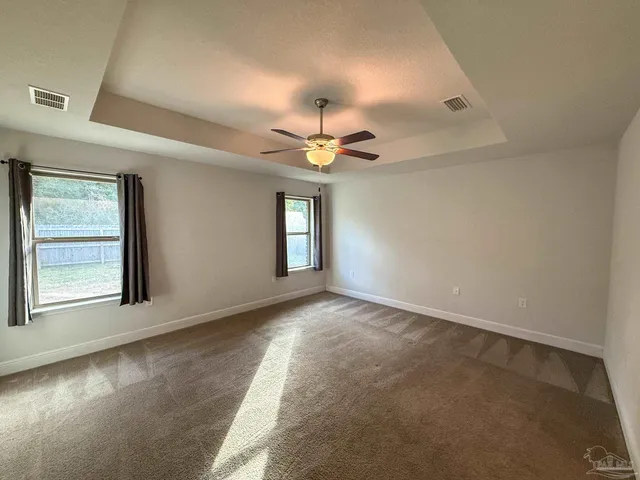 an empty room with windows and ceiling fan