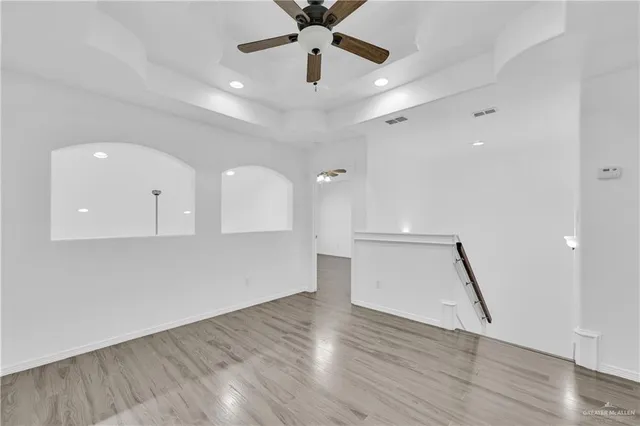 an empty room with wooden floor and a ceiling fan