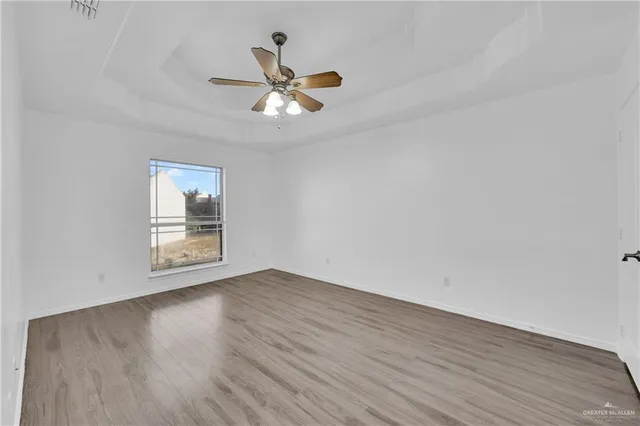 a view of empty room with wooden floor and fan