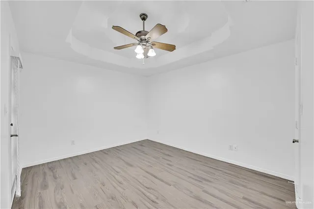 an empty room with wooden floor fan and windows