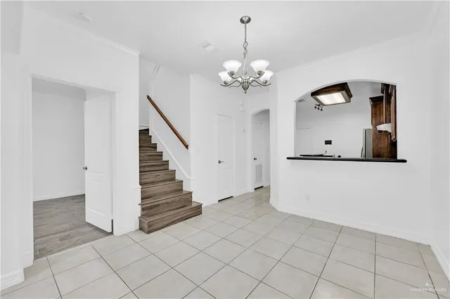 a view of an empty room with wooden floor and a chandelier