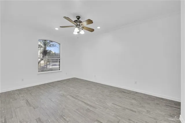 an empty room with wooden floor closet and fan