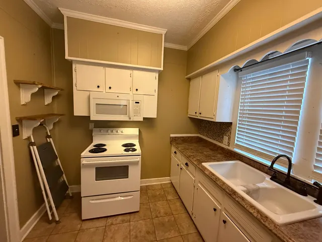 a kitchen with granite countertop a sink a stove and washer