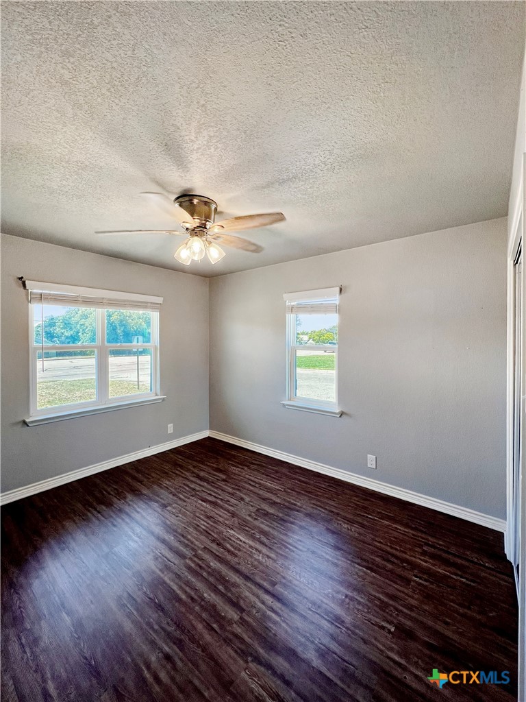 1311 West Main Street Gatesville, TX 76528 - Photo 23 of 30 an empty room with wooden floor chandelier fan and windows