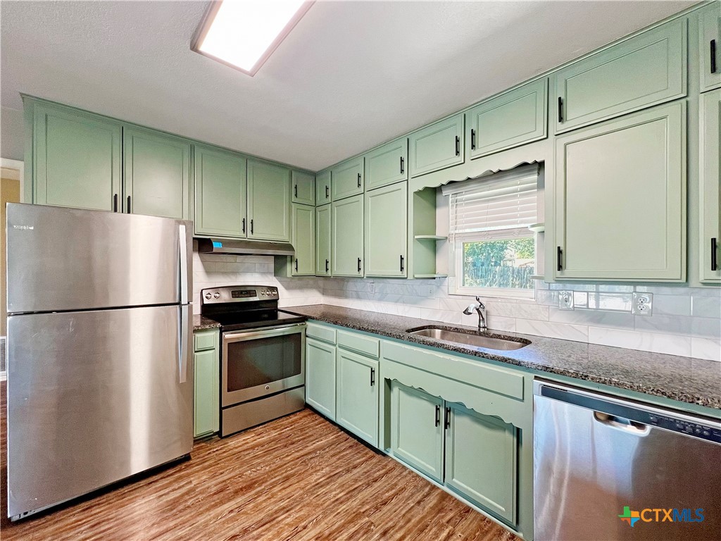 1311 West Main Street Gatesville, TX 76528 - Photo 7 of 30 a kitchen with stainless steel appliances a sink cabinets and a wooden floor