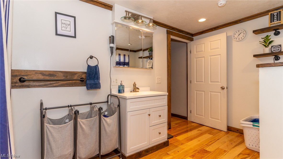 13962 Nickel Plate Road Logan, OH 43138 - Photo 22 of 46 Bathroom featuring crown molding, oversized vanity, and hardwood / wood-style floors