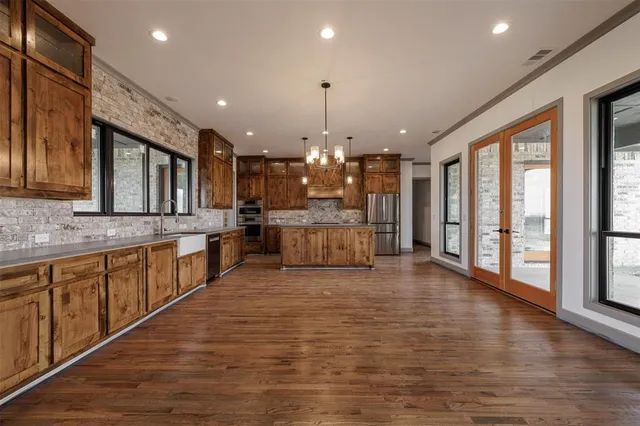 a large kitchen with granite countertop a large counter top a sink stainless steel appliances and cabinets