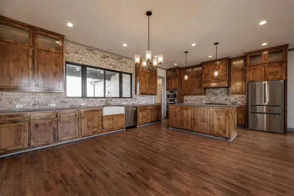 a large kitchen with stainless steel appliances kitchen island a large counter top a sink cabinets and a wooden floor