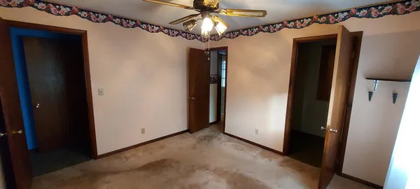 a view of a hallway with a chandelier fan and closet