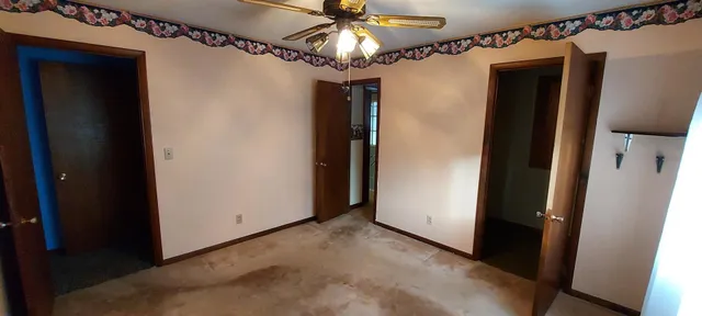 a view of a hallway with a chandelier fan and closet