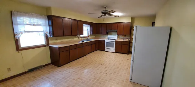 a kitchen with stainless steel appliances granite countertop a refrigerator a sink dishwasher a stove and a dining table with wooden floor