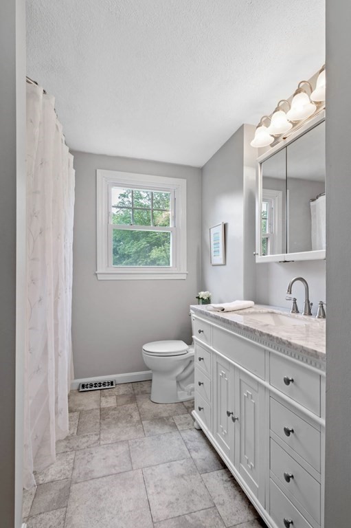 10 Wyman Road Billerica, MA 01821 - Photo 15 of 33 a spacious bathroom with a granite countertop toilet a sink a mirror and a window