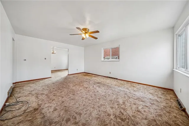 an empty room with a window and ceiling fan