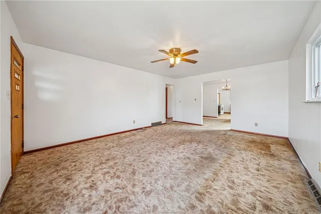 a view of empty room with a window and a ceiling fan