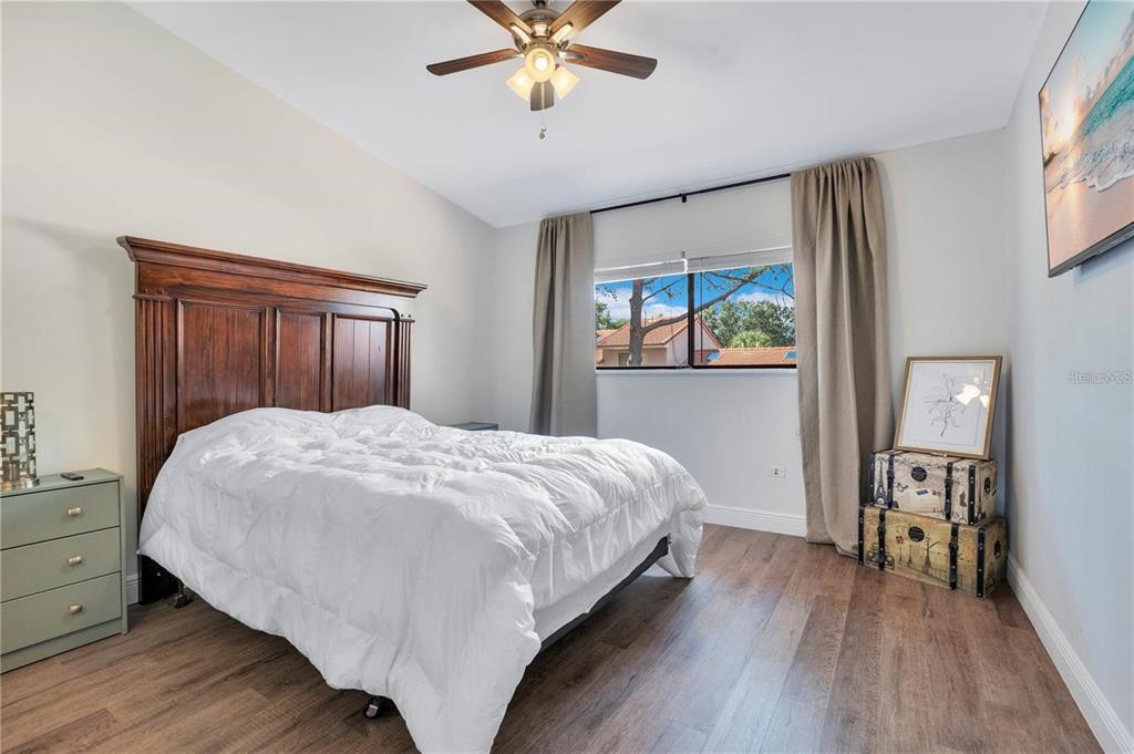 7736 Windbreak Road Orlando, FL 32819 - Photo 25 of 43 a bedroom with a large bed a chandelier and a window