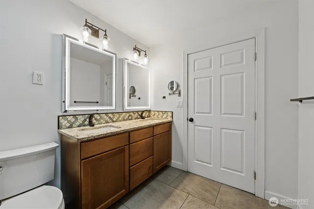 a bathroom with a granite countertop sink toilet a mirror and shower