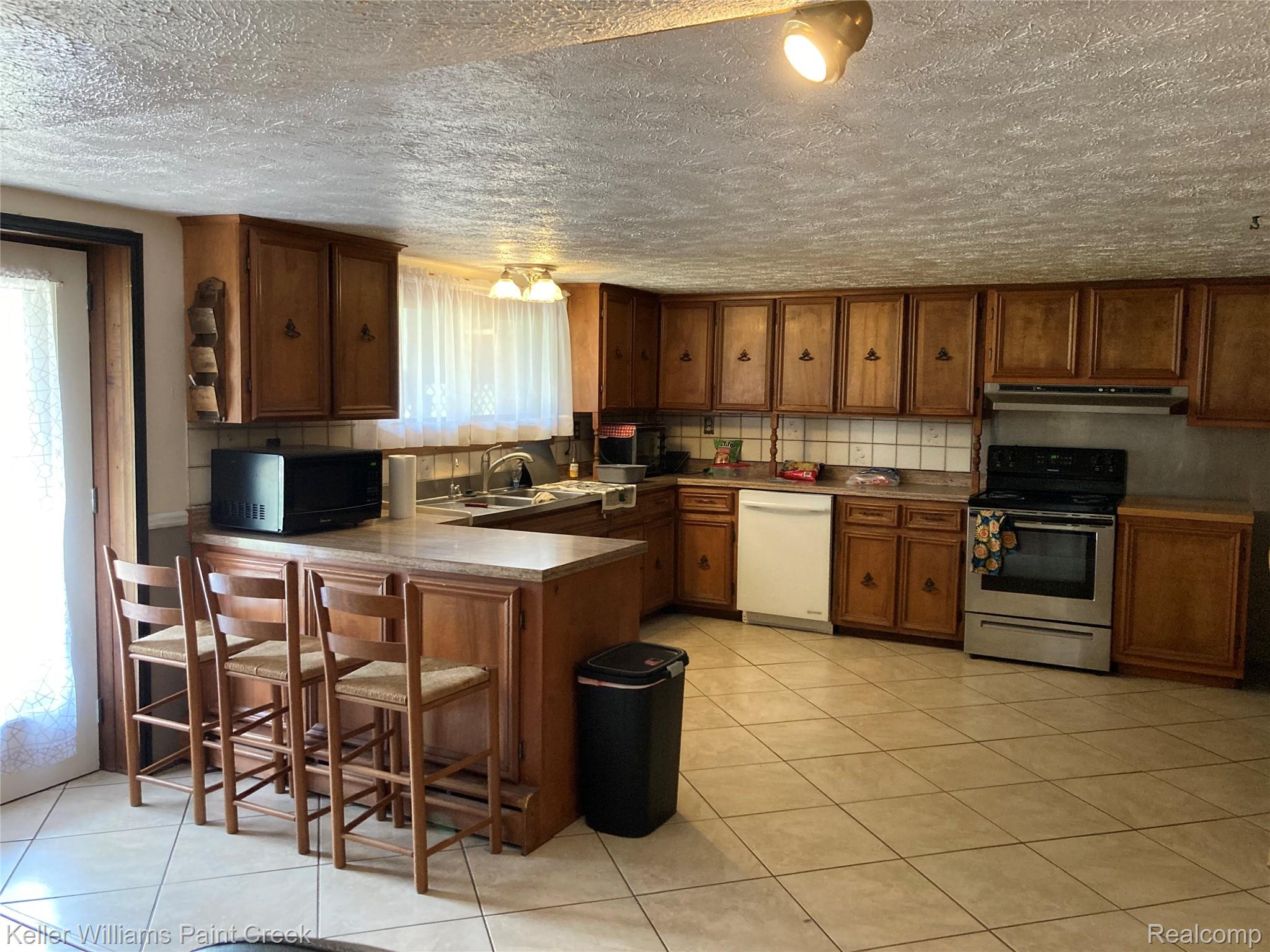 42891 Bemis Road Belleville, MI 48111 - Photo 17 of 51 Kitchen with wood finish cabinets, stainless steel electric range oven, a peninsula, black microwave, and dishwasher