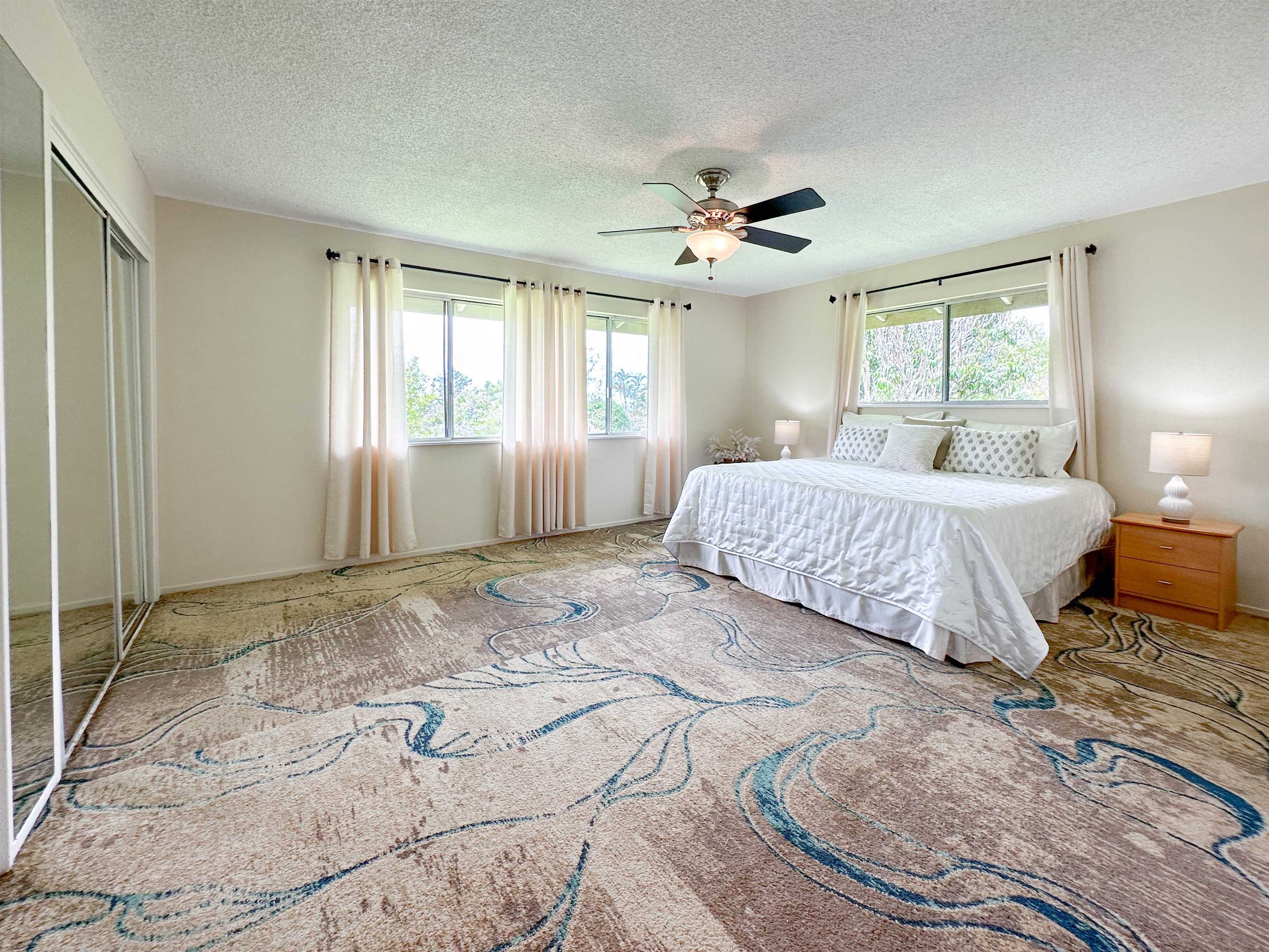 1875 Lower Kula Road Kula, HI 96790 - Photo 20 of 36 a spacious bedroom with a large bed a chandelier and windows