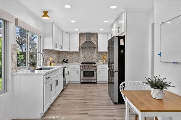 a large kitchen with stainless steel appliances a large counter top a stove a chimney a sink and a refrigerator