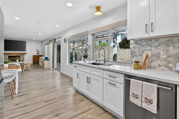 a view of a white house next to a yard with potted plants