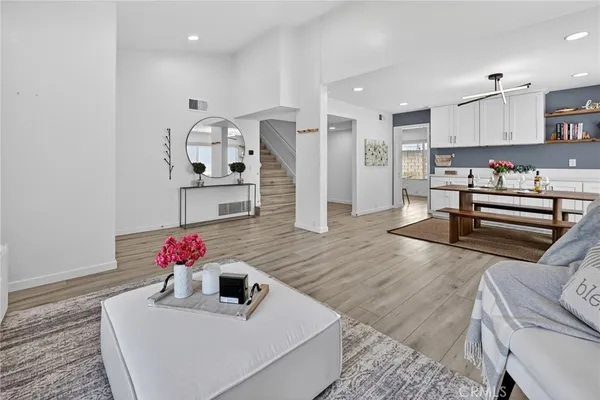 a kitchen with stainless steel appliances kitchen island granite countertop a sink dishwasher and white cabinets with wooden floor