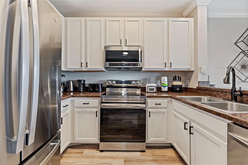 14200 Avalon Road, Unit 409 Winter Garden, FL 34787 - Photo 12 of 33 a kitchen with granite countertop white cabinets and stainless steel appliances