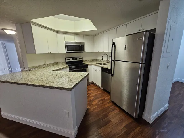 a kitchen with granite countertop a refrigerator a sink a stove a microwave and island