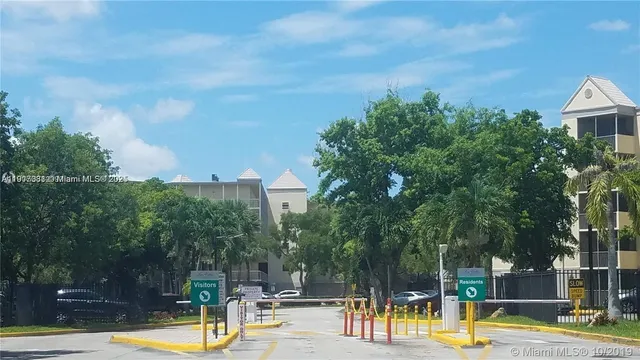 a view of a swimming pool with a patio and a yard with plants and large trees