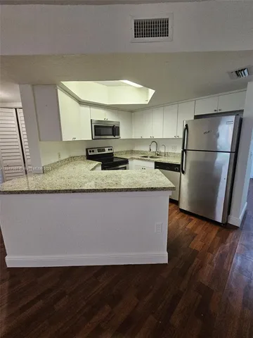 a view of a kitchen with a sink dishwasher refrigerator stove and wooden floor