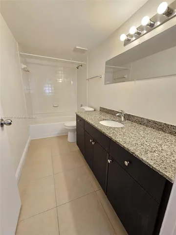 a bathroom with a granite countertop sink a toilet and bathtub