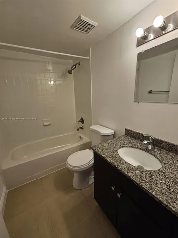 a bathroom with a granite countertop sink toilet a mirror and shower