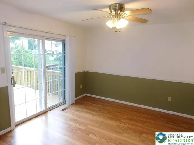 a view of empty room with wooden floor and fan