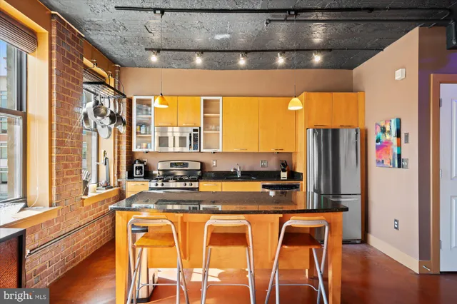 a view of a kitchen with kitchen island granite countertop a large window and stainless steel appliances