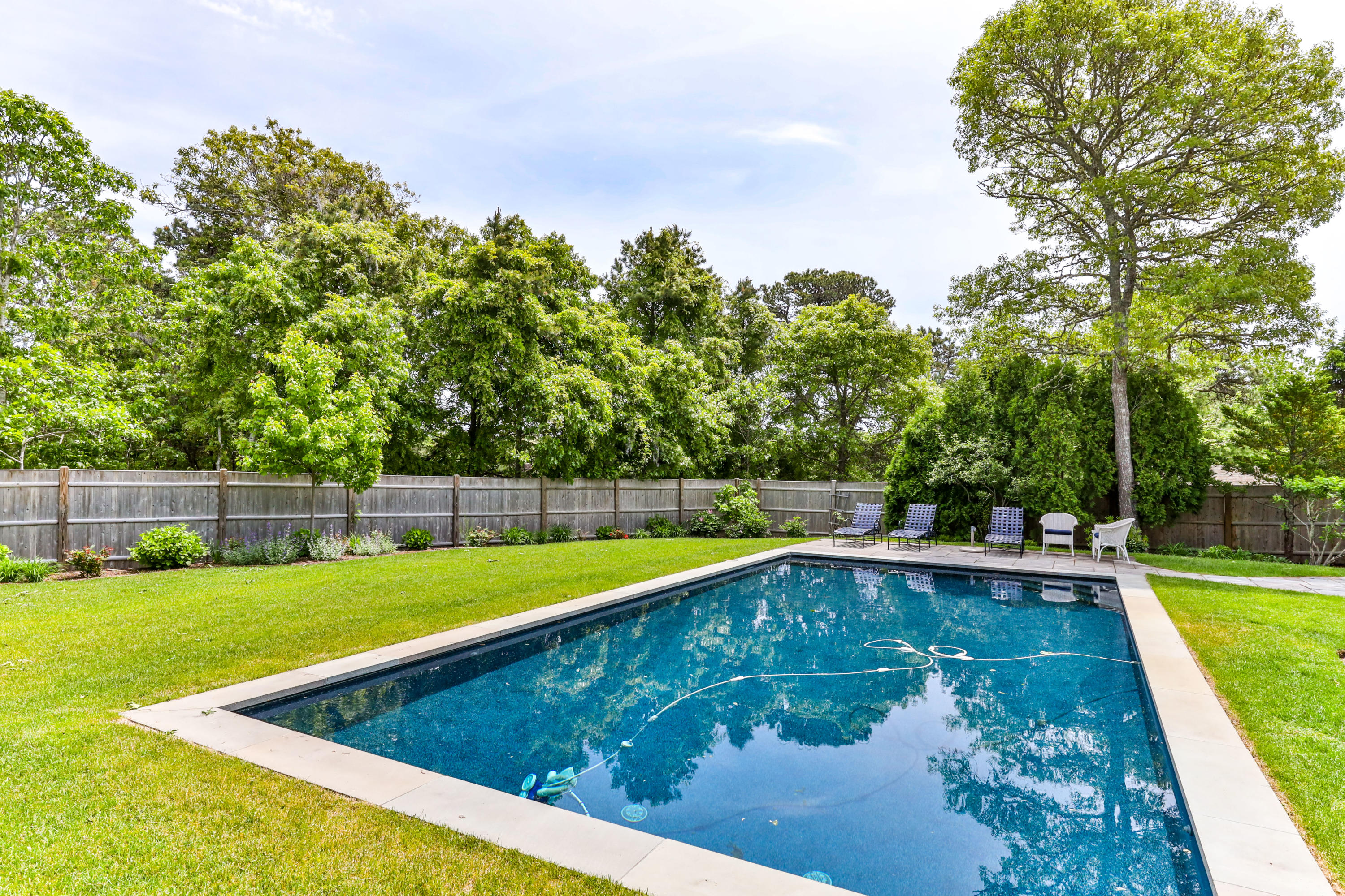 88 Round Cove Road Chatham, MA 02633 - Photo 26 of 58 a view of a swimming pool with a yard and trees in the background