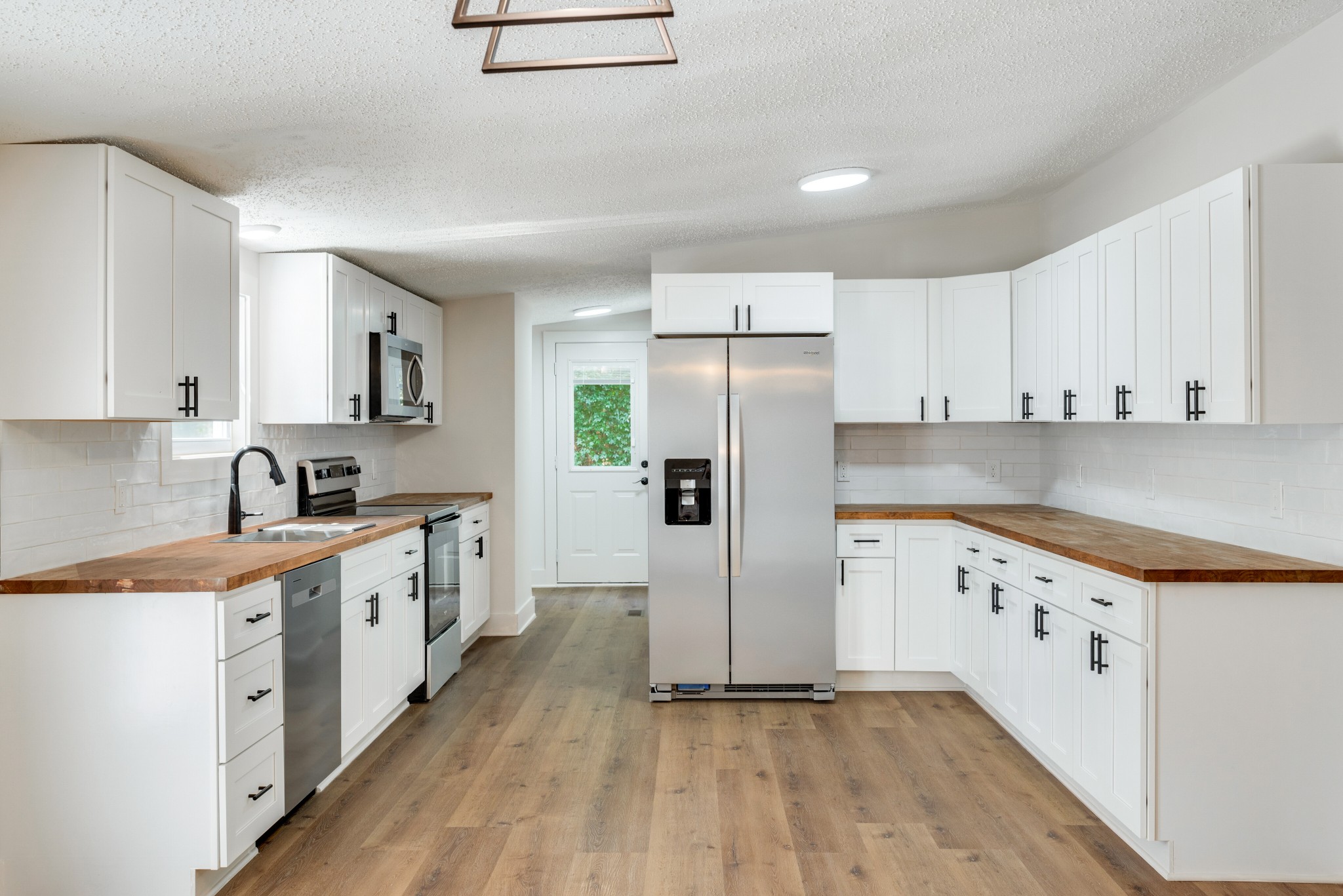 9064 New Chapel Road Springfield, TN 37172 - Photo 6 of 33 a kitchen with granite countertop a sink a refrigerator a stove and white cabinets